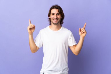 Mor arka planda izole edilmiş genç yakışıklı adam harika bir fikre işaret ediyor.