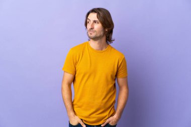 Mor arka planda soyutlanmış genç yakışıklı bir adam.