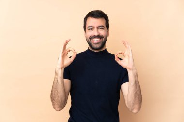 Kafkas yakışıklı adam izole edilmiş arka planda parmaklarıyla iyi bir işaret gösteriyor.