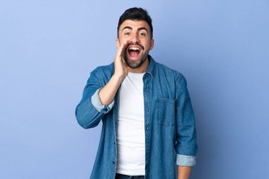 İzole edilmiş mavi arka planda beyaz bir adam ağzı açık bağırıyor.