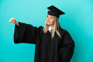 Tecrit edilmiş mavi arka planda genç üniversite mezunu.