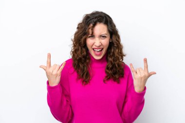 Beyaz arka planda izole edilmiş genç beyaz kadın boynuz hareketi yapıyor.