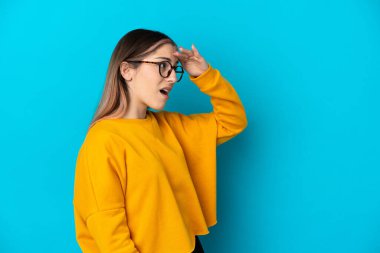 Mavi arka planda mahsur kalmış beyaz bir kadın. Sürpriz bir ifadeyle yan tarafa bakarken.