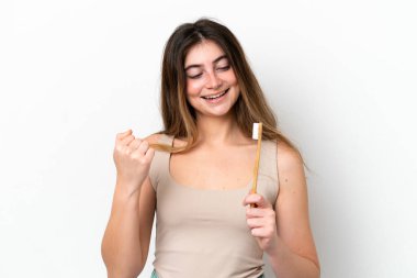 Beyaz arka planda dişlerini fırçalayan beyaz kadın zaferi kutluyor.