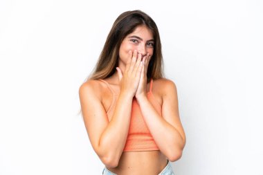 Beyaz arka planda izole edilmiş genç beyaz bir kadın mutlu ve gülümseyen elleriyle ağzını kapatıyor.