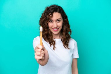 Mavi arka planda dişlerini fırçalayan beyaz kadın mutlu bir ifadeyle izole edilmiş.