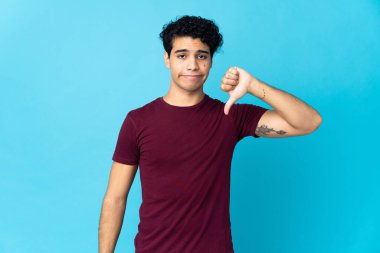 Genç Venezuelalı adam mavi arka planda izole edildi.