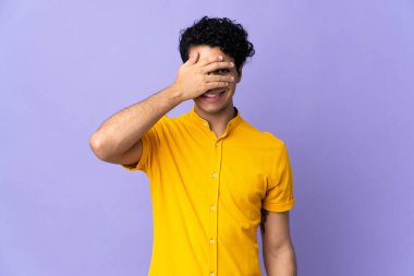 Genç Venezuelalı bir adam mor arka planda izole edilmiş, gözleri kapalı ve gülümsüyor.