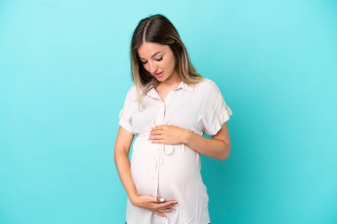 Genç Romen kadın mavi arka planda izole edilmiş hamile.