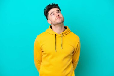 Kafkasyalı genç adam mavi arka planda izole edilmiş ve yukarı bakıyor.