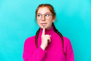 Mavi arka planda gözlüklü ve yukarı bakan genç, kırmızımsı bir kadın.