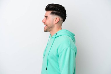 Beyaz arka planda izole genç beyaz adam yan pozisyonda gülerek