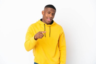 Beyaz arka planda izole edilmiş genç Latin adam şaşırmış ve ön tarafı işaret ediyor.