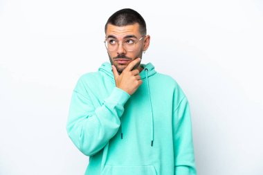 Beyaz arka planda izole edilmiş genç beyaz adam yukarı bakarken bir fikir düşünüyor.