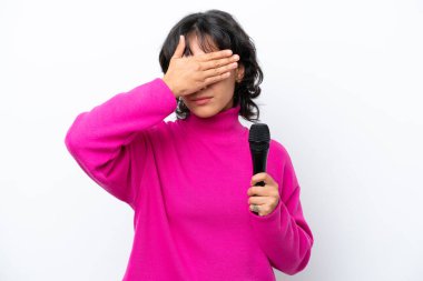 Genç Arjantinli şarkıcı kadın, beyaz arka planda gözleri elleriyle kapatıyor. Bir şey görmek istemiyorum.