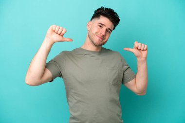 Kafkasyalı genç adam mavi arka planda soyutlanmış gururlu ve kendini beğenmiş.