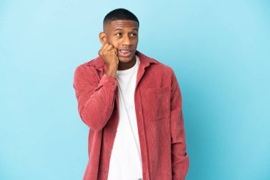 Mavi arka plandaki genç latin adam biraz gergin.