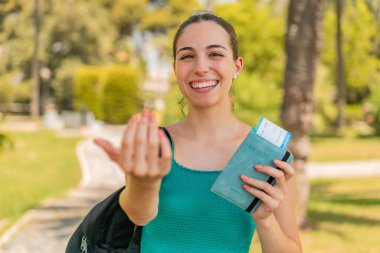 Dışarıda elinde pasaport olan genç ve güzel bir kadın geliyor.