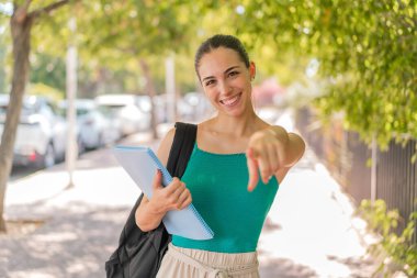 Açık havadaki genç ve güzel bir bayan kendine güvenen bir ifadeyle seni işaret ediyor.