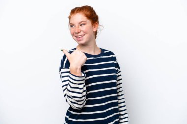 Beyaz arka planda izole edilmiş genç bir kadın bir ürünü sunmak için kenarı işaret ediyor.