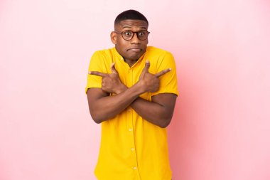 Pembe arka planda izole edilmiş genç latin adam, yandakilerin kuşkuları olduğunu gösteriyor.