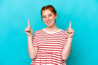 Mavi arka planda izole edilmiş genç bir kadın harika bir fikre işaret ediyor.