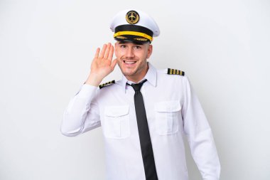 Kafkasyalı uçak pilotu beyaz arka planda izole edilmiş bir şekilde elini kulağına koyarak bir şey dinliyor.