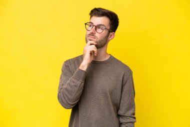 Genç beyaz adam sarı arka planda izole edilmiş ve yukarı bakıyor.