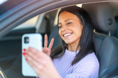 Dışarıdaki bir arabada cep telefonu kullanan genç bir kadın.