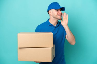 Teslimatçı beyaz adam mavi arka planda izole edilmiş ağzı sonuna kadar açık bağırıyor.