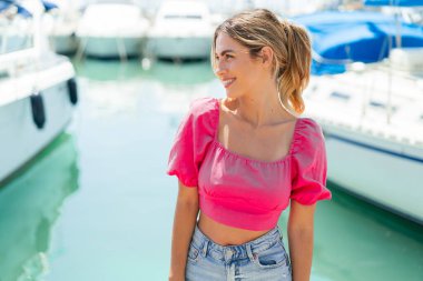 Açık havada genç sarışın bir kadın Neşeli bir ifadeyle