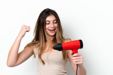 Young caucasian woman holding a hairdryer isolated on white background celebrating a victory