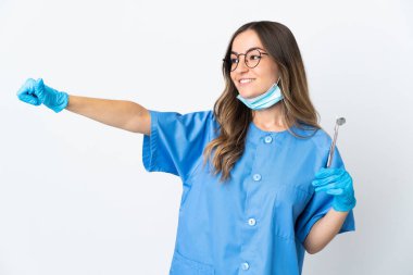 Pembe arka planda izole edilmiş araçları elinde tutan Romen kadın diş hekimi iyi niyet gösterisi yapıyor