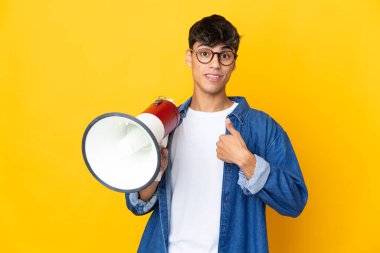 Sarı arka planda, elinde megafonla, şaşırmış bir yüz ifadesi olan genç bir adam.