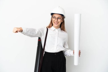 Miğferli ve elinde planları olan genç bir mimar beyaz arka planda izole edilmiş bir şekilde el hareketi yapıyor.