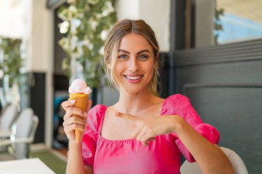 Açık havada kornet dondurması olan genç sarışın kadın.