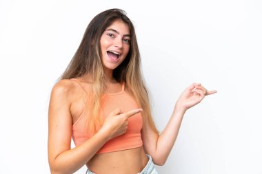 Beyaz arka planda izole edilmiş genç beyaz kadın şaşırmış ve işaret ediyor.