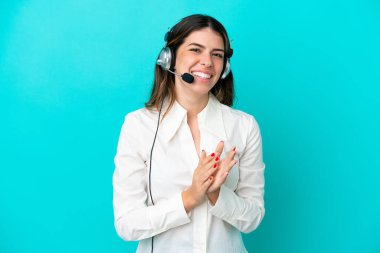 Tele pazarlamacı İtalyan kadın kulaklıkla çalışıyor mavi arka planda izole edilmiş bir şekilde bir konferansta sunumdan sonra alkışlıyorlar.