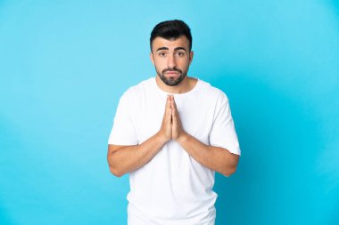 İzole edilmiş mavi geçmişi olan beyaz bir adam avuç içlerini bir arada tutar. İnsan bir şey ister.