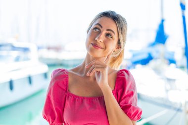 Açık havada genç sarışın bir kadın yukarı bakarken bir fikir düşünüyor.