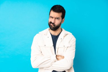 Mavi arka planda beyaz kadife ceketli yakışıklı bir adam üzgün.