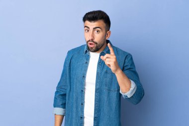 İzole edilmiş mavi arka plan üzerinde beyaz bir adam parmak kaldırarak çözümü anlamaya çalışıyor.