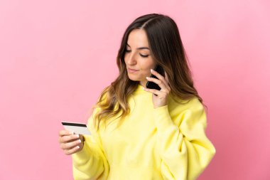Genç Romen kadın, kredi kartıyla pembe arka plan alışverişinde izole edilmiş