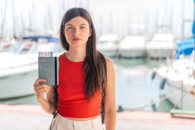 Genç, güzel Ukraynalı bir kadın, elinde pasaport tutarken üzgün bir ifadeyle.