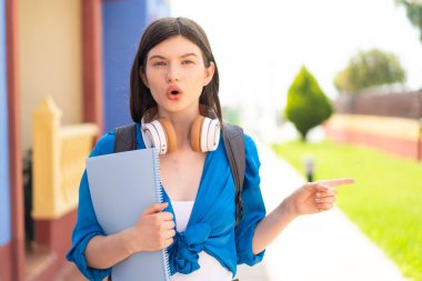 Genç, güzel, Ukraynalı bir bayan öğrenci açık havada şaşırmış ve işaret ediyor.