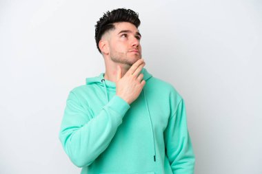 Beyaz arka planda izole edilmiş genç beyaz adam gülümserken yukarı bakıyor.