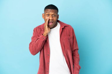 Mavi arka planda mahsur kalmış genç latin adam şaşırmış ve şok olmuş bir yüz ifadesi var.