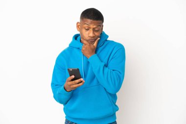 Genç Latin bir adam beyaz arka planda izole edilmiş düşünüyor ve bir mesaj gönderiyor.
