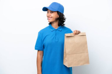 İzole edilmiş arka planda bir paket yiyecek taşıyan genç ve güzel kurye kadın.  