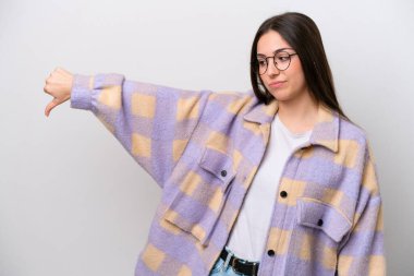 Young girl isolated on white background showing thumb down with negative expression
